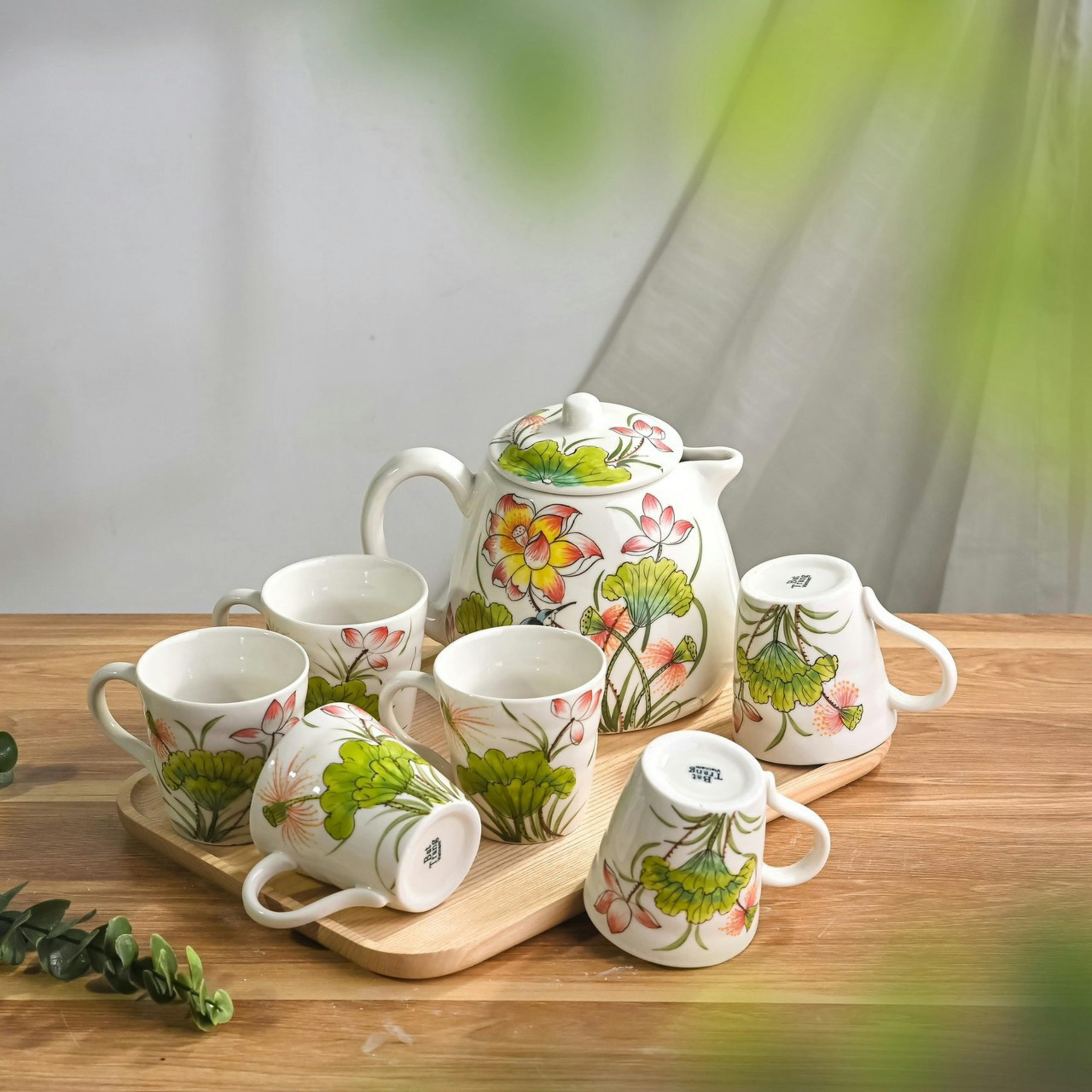 Beautiful handmade floral ceramic tea set with cups and teapot on a wooden tray. Perfect for stylish interiors.