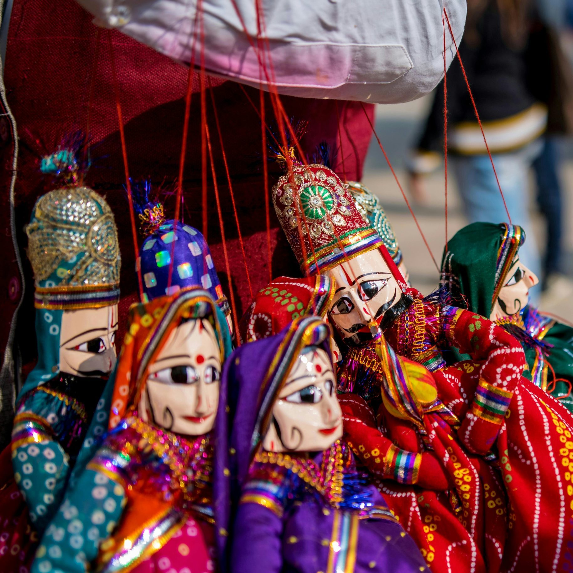 Vibrant traditional Indian puppets with intricate designs hung for sale in a local market.