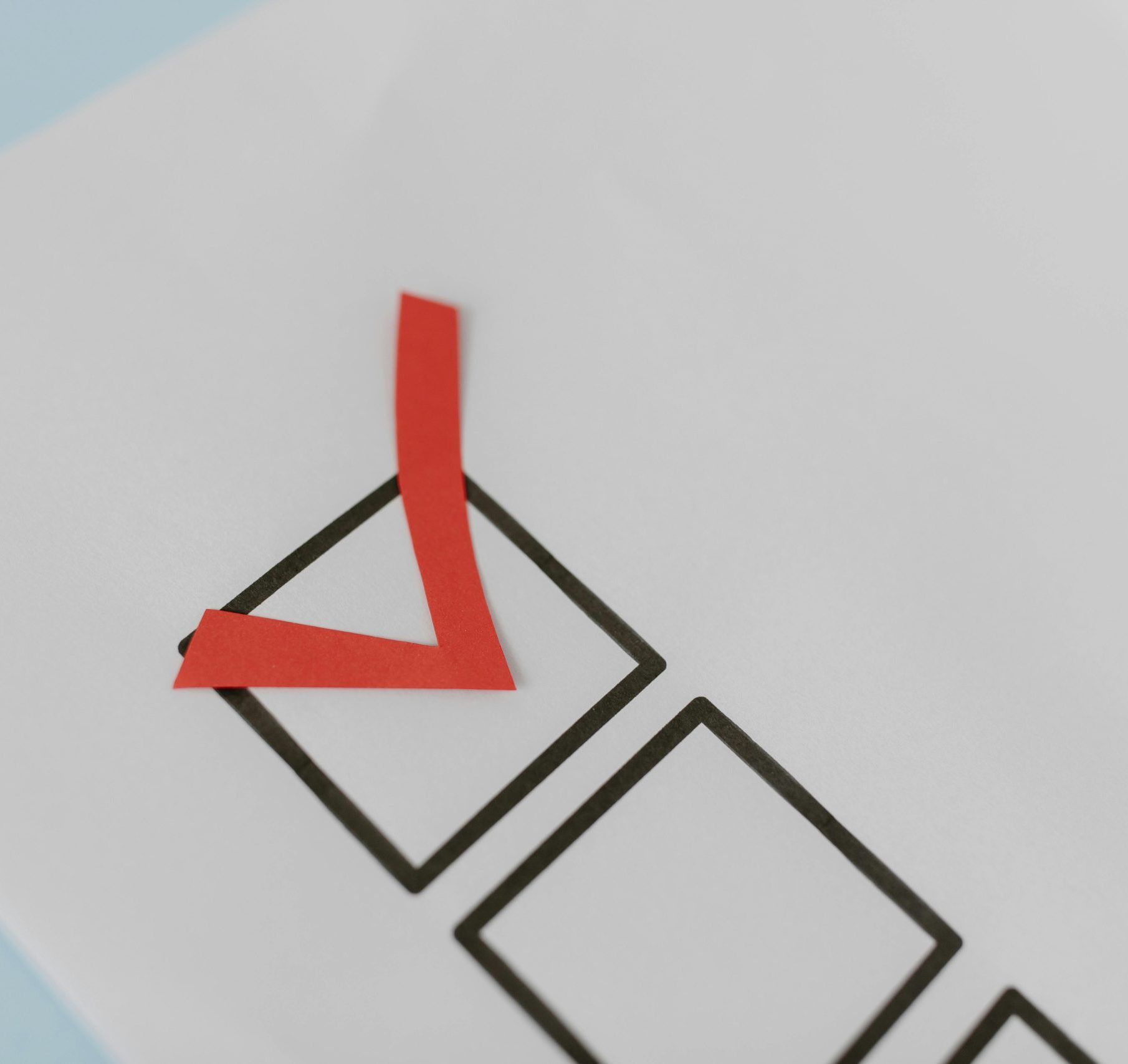 Close-up of a red check mark on a crisp white paper with black boxes, symbolizing completion.